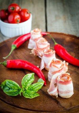 ahşap tahta üzerinde domuz pastırması şeritler haddelenmiş