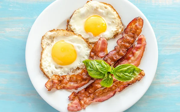 Uova fritte con pancetta sul tavolo di legno — Foto Stock