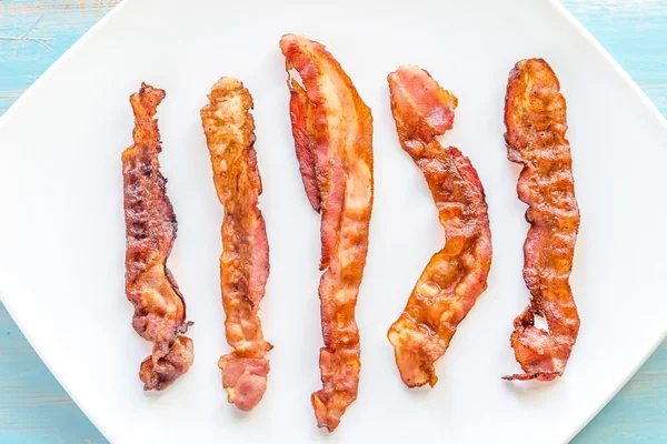 Fried bacon strips on the square plate — Stock Photo, Image