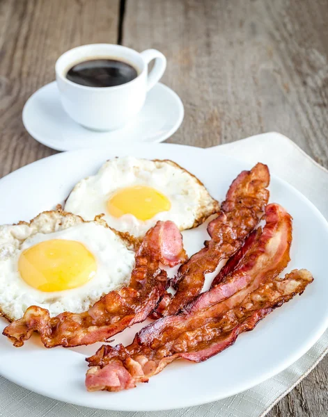 Fried eggs with bacon on the wooden table — Stock Photo, Image
