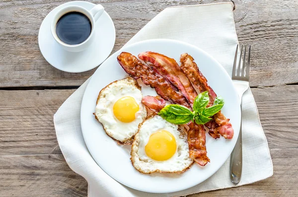 Sázená vejce s anglickou slaninou na dřevěný stůl — Stock fotografie
