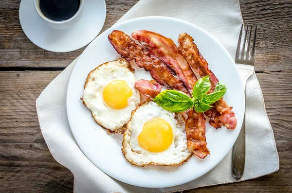 Uova fritte con pancetta sul tavolo di legno — Foto Stock