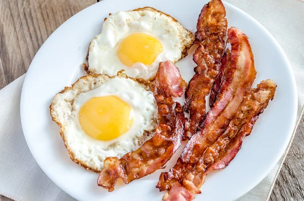 Uova fritte con pancetta sul tavolo di legno — Foto Stock