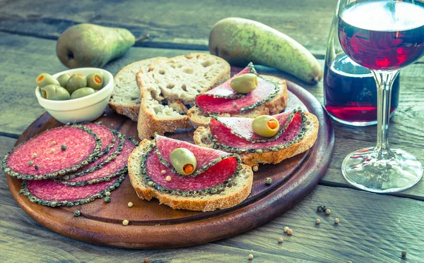 Slices of italian salami with pears and wine — Stock Photo, Image