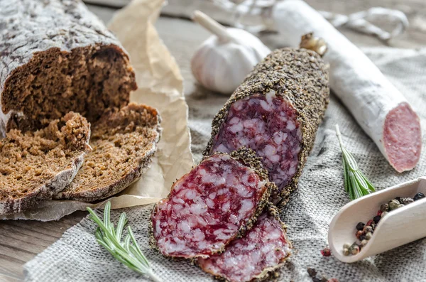 Slices of saucisson and spanish salami on the sackcloth — Stock Photo, Image