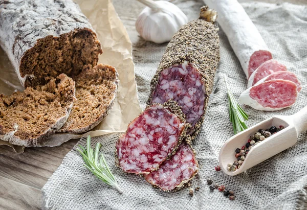 Slices of saucisson and spanish salami on the sackcloth — Stock Photo, Image