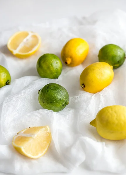 Lemons and limes on the white background: whole fruits and cross — Stock Photo, Image