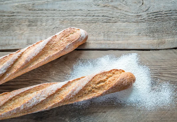 Due baguette di grano integrale sullo sfondo di legno — Foto Stock