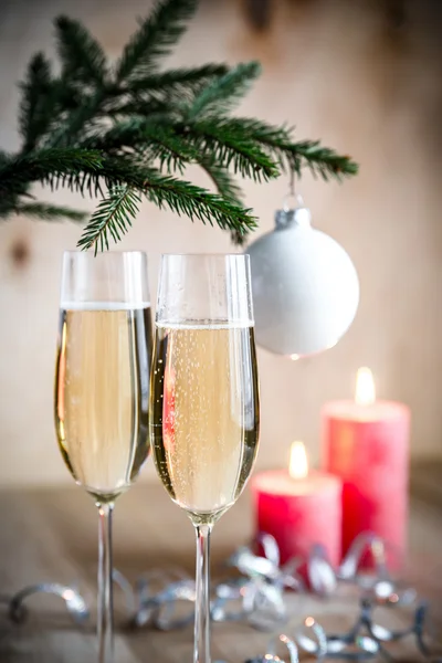 Glasses of champagne under decorated christmas tree branch — Stock Photo, Image