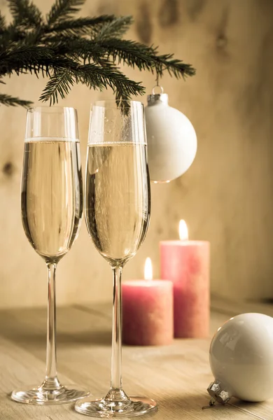 Glasses of champagne under decorated christmas tree branch — Stock Photo, Image