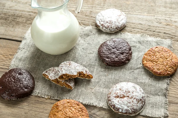 Glazed gingerbread cakes with pitcher of milk — Stock Photo, Image