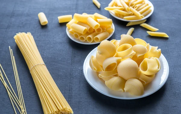Olika typer av pasta på den mörka bakgrunden — Stockfoto