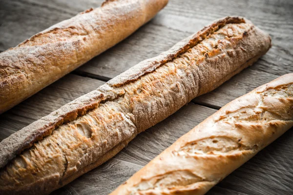 Tres baguettes en el fondo de madera — Foto de Stock