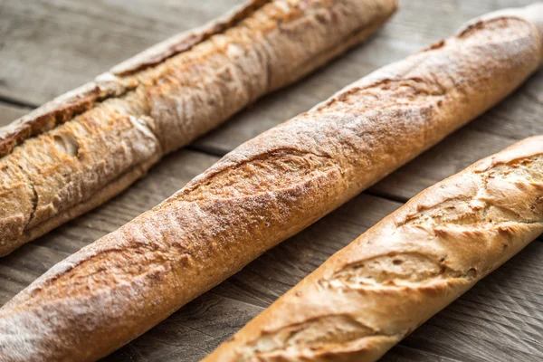 Tre baguette sullo sfondo di legno — Foto Stock