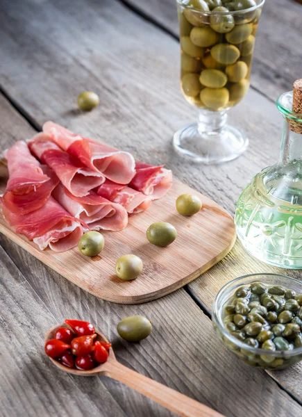 Jamón met kappertjes en olijven op de houten bord — Stockfoto