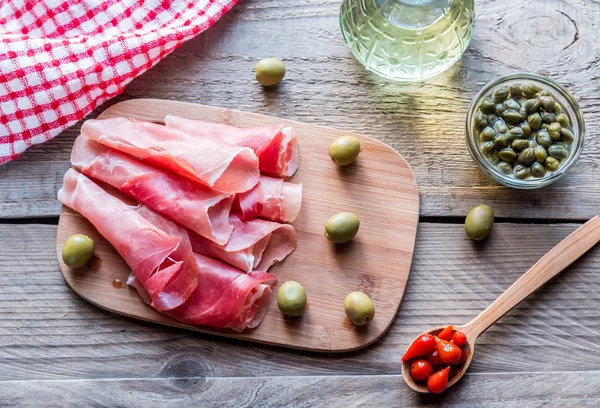 Jamon con capperi e olive sulla tavola di legno — Foto Stock