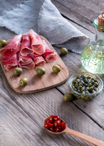 Jamón met kappertjes en olijven op de houten bord — Stockfoto