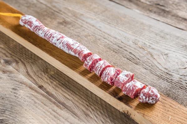 Snij Spaanse salami op de houten plank — Stockfoto