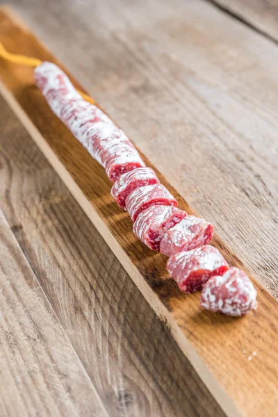 Snij Spaanse salami op de houten plank — Stockfoto