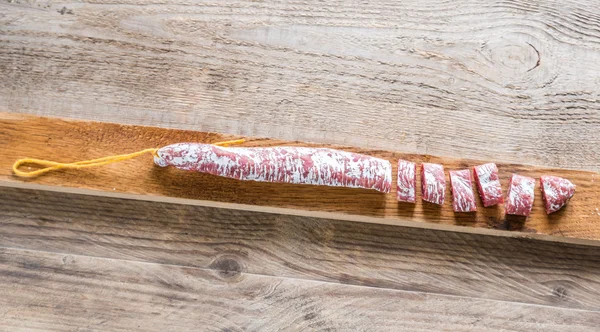 Snij Spaanse salami op de houten plank — Stockfoto