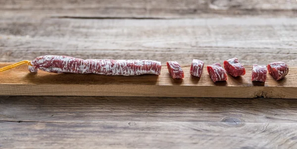 Snij Spaanse salami op de houten plank — Stockfoto