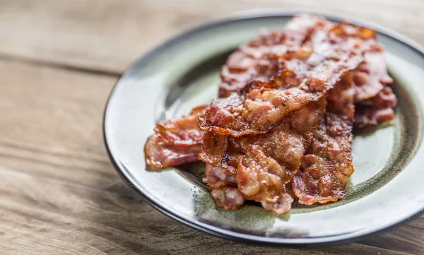 Montón de tiras de tocino frito en el plato —  Fotos de Stock