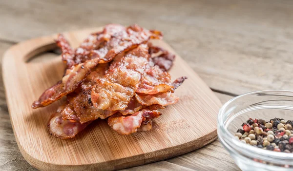 Stapel van gebakken bacon strips op de houten bord — Stockfoto