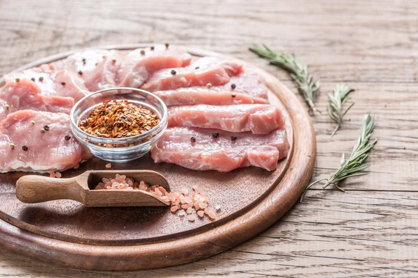 Bifes de porco crus na tábua de madeira — Fotografia de Stock