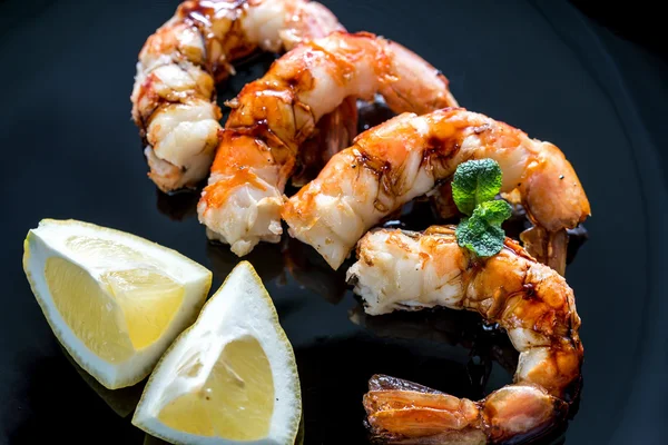 Fried shrimps with lemon wedges on the black background — Stock Photo, Image