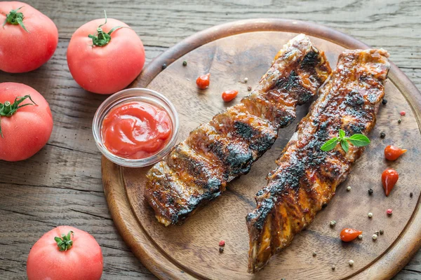 Côtes de porc grillées aux tomates sur la planche de bois — Photo