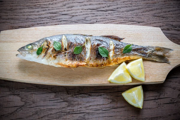 Gegrilde zeebaars op de houten bord — Stockfoto