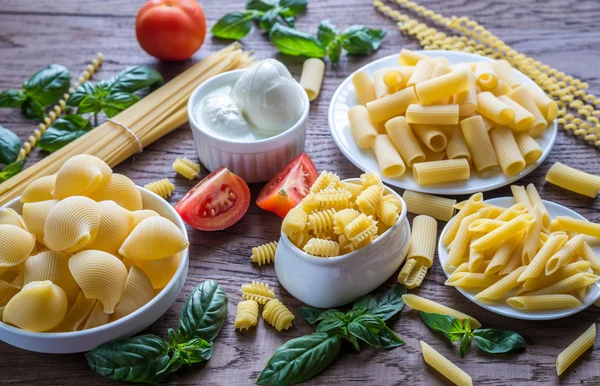Various types of pasta on the wooden background — Stock Photo, Image