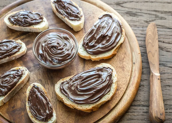 Segmenten van stokbrood met chocolade crème op de houten bord — Stockfoto