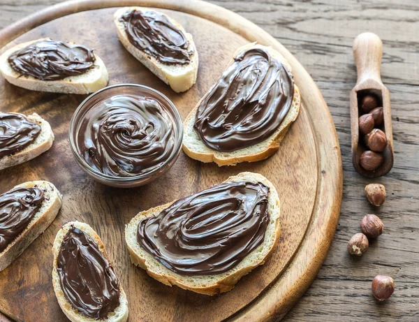 Skivor av baguette med choklad grädde i trä styrelsen — Stockfoto