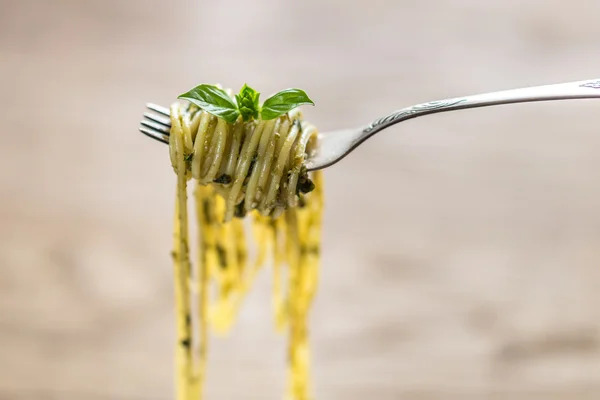Спагетті з соусом песто та листям базиліка на вилці — стокове фото