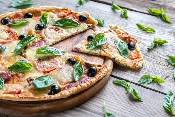 Cut pizza on the wooden board — Stock Photo, Image