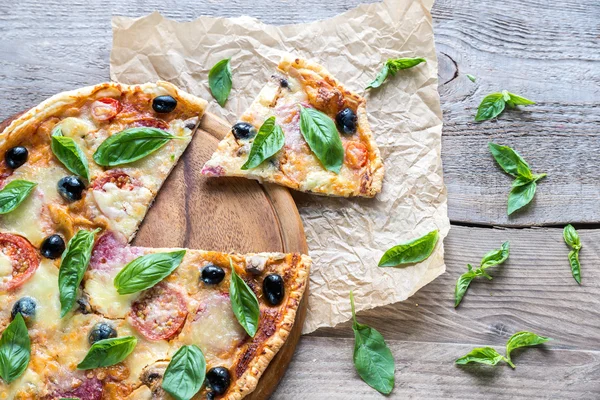 Cut pizza on the wooden board — Stock Photo, Image