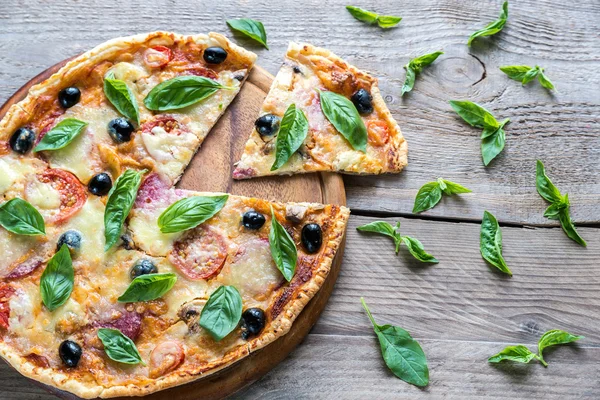 Cut pizza on the wooden board — Stock Photo, Image