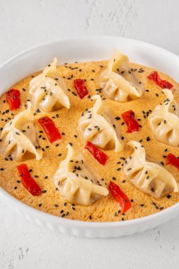 Soluk turuncu Tom Yum sosuyla servis edilen yedi narin gyoza biber aksanıyla.