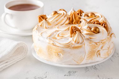 Beyaz arka planda çayın yanında servis edilen yanmış kremalı lüks Medovik keki.