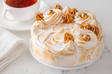 Beyaz arka planda çayın yanında servis edilen yanmış kremalı lüks Medovik keki.