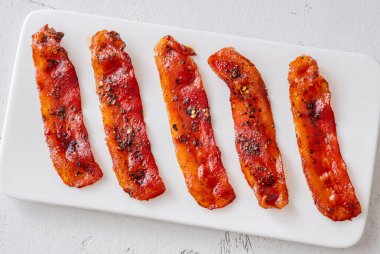 Çatlamış biberli tatlı pastırma ve temiz modern yüzeyde kırmızı biber taneleri.