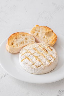 Eritilmiş kremabert otları ve parlak arka planda ekmeğin yer aldığı zarif peynir tabağı.