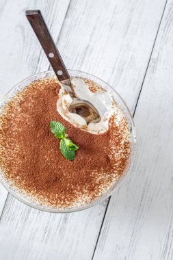 Kaşıkla kaşık kaşık kaşık tiramisu kahveye batırılmış mascarpone kreması ve kakao sosunu gösteriyor.