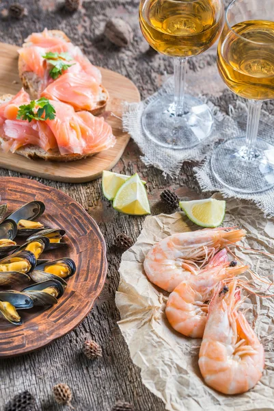 Mariscos con dos copas de vino blanco en la mesa de madera — Foto de Stock