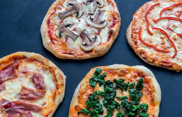 Mini pizzas with various toppings on the wooden board — Stock Photo, Image
