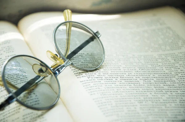 Leitura de óculos deitado em um livro aberto — Fotografia de Stock