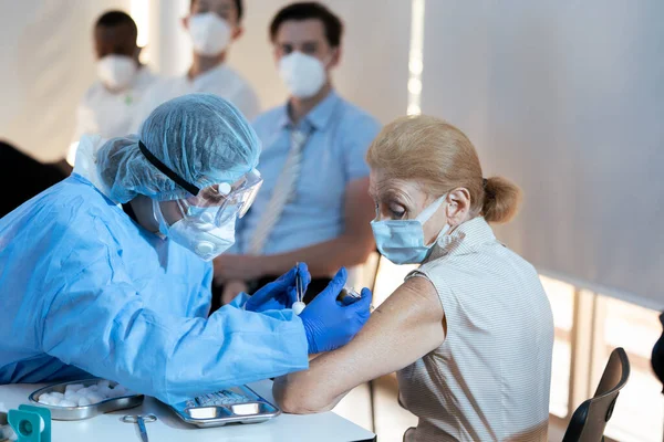 Kafkasyalı yaşlı kadın Coronavirus salgınını önlemek için aşı istasyonunda ilk doz COVID-19 antiviral aşıyı aldı. Bağışıklık sistemi, Covid-19, Coronavirus global pandemi