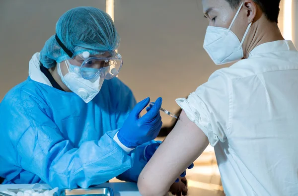 Aşıyı kapat. Asyalı doktor Coronavirüs salgınını önlemek için aşı istasyonunda ya da hastanede aşılanmaya COVID-19 antiviral aşı enjekte etmek için şırınga kullanıyor.