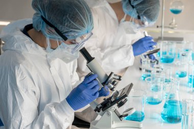 Kadın bilim adamları kovid 19 virüs aşısını tıbbi bir laboratuvarda araştırmak için mikroskop kullanıyorlar. Bir doktor kimya laboratuvarında koronavirüsü araştırmak için biyoteknoloji kullanır. İlaç bilimi kavramları